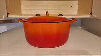 Dutch oven front view with lid showing orange-red gradient and side handles