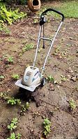 Full view of corded electric tiller cultivator standing upright on soil