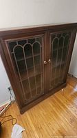 Full view of bookcase showing twin glass doors and wood frame