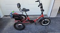 Full left side view of red Liberty Trike showing front motor wheel, rear basket with battery, saddle with backrest