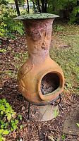 Full view of clay chiminea on stand in garden setting