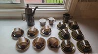 Full lot showing coffee pot, brown and green cup sets, creamers and sugar bowl