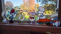 Group shot showing five stained glass figures lined on window sill