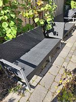 Two black resin wicker patio sofas on stone patio