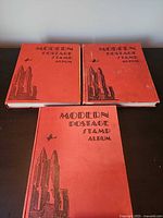 Front view of three red Modern Postage Stamp Albums