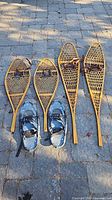 All three pairs of snowshoes laid out side by side on stone surface