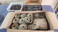 Three containers: tub of spiral nails, carton of coil nails, box of flooring staples
