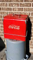 Full view of front of red Coca-Cola cooler showing logo, handle and corner caps