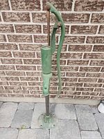 Full front view of green cast iron hand water pump showing handle and base