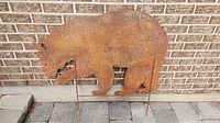 Front view of full metal bear silhouette leaning against brick wall