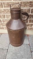 Front view of brown metal milk can showing handle and lid