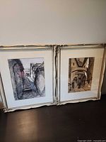 Both framed drawings leaning against wall