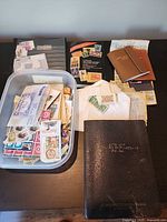 Overview of lot: plastic tub of stamps, black stockbook, two brown stockbooks, additional album pages