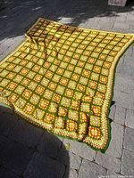 Full view of crochet blanket laid out on stone patio