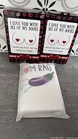 Two boxed boob-graphic towels and one eggplant-graphic towel package
