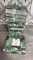 Stack of shrink-wrapped green tropical leaf napkin packs