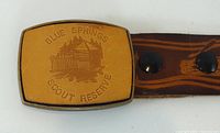 Tan leather-faced buckle with Blue Springs Scout Reserve emblem attached to brown leather strap