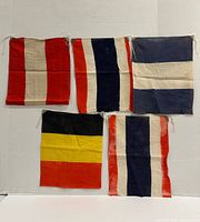 Five small cotton flags laid flat: four maritime signal flags in assorted red, white, blue patterns and one Belgian flag (black, yellow, red)