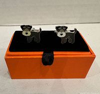 Front view of Schnauzer dog cufflinks on black velvet insert atop orange box base