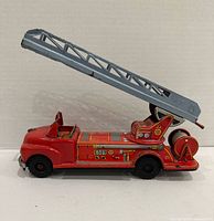 Left side view of red tin fire truck with raised grey ladder