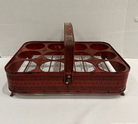 Full view of red metal bottle rack showing handle, eight circular openings, and overall condition