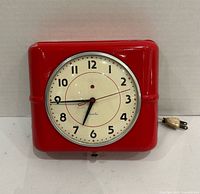 Front view of red Westclox Belfast electric wall clock with attached cord and plug