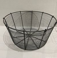 Top angled view of round black wire basket showing open-weave construction