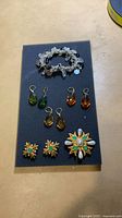 Overview of entire lot on foam board: bracelet, six teardrop earrings, starburst brooch, clip-on earrings