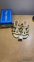 Top view of pair of sandals beside blue Scholl made in Italy box