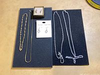Overall lot view showing earrings in box and on card with four necklaces
