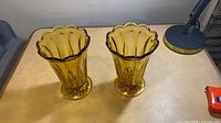 Two matching amber pressed glass vases on table