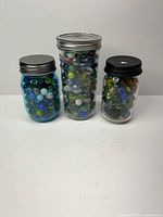 Three jars filled with assorted marbles