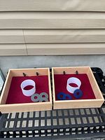 Both washer toss boxes open, showing PVC cups and washers inside on red felt