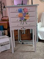 Front view of painted wood dresser showing four drawers with hydrangea design and knobs