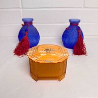 Front view of two blue vases with red tassels and amber jewelry box