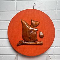 Front view showing carved squirrel, acorn and branch on orange burlap round plaque