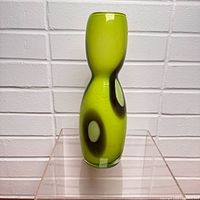 Front view of green art glass vase showing hourglass form and interior oval accent
