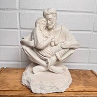 Front view of white resin Holy Family statue on wooden surface