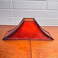 Side view of red lamp shade showing trapezoid form and stitching