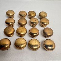 Top view of all 16 brass knobs showing wear and patina
