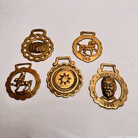 Group shot of five brass horse brasses