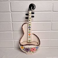 Front view of ceramic violin wall pocket showing overall shape and floral design