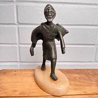front view of metal worker statue on oval stone base