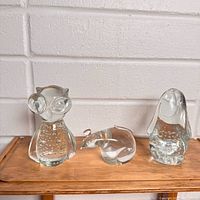 Group shot of three clear crystal animal figurines on wood surface