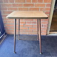 Front view of square laminate top telephone table with metal legs and rod rack