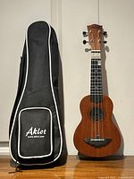 Ukulele standing beside gig bag to show both items