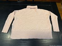 Sweater laid flat back view showing full garment and ribbed hem