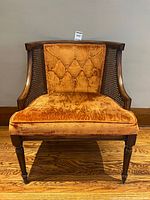 Front view of orange velvet cane-back chair showing upholstery, frame and legs