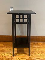 Front view of tall black wooden plant stand