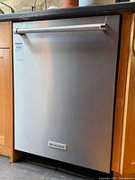 Front view of stainless steel KitchenAid dishwasher installed between wood cabinets